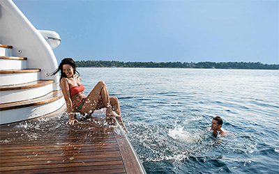 Guy in the sea and girl on swimming platform whilst on their superyacht charter Ibiza and Formentera